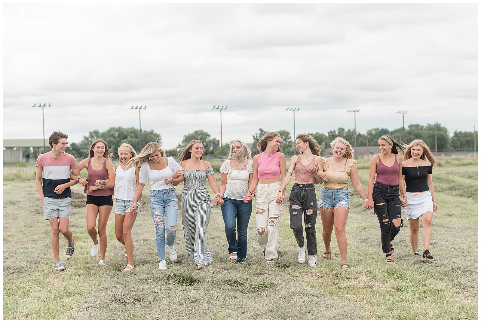 eleven senior spokesmodels wearing black, white, blue, and pink with arms interlocked walking toward camera in field in lancaster pennsylvania