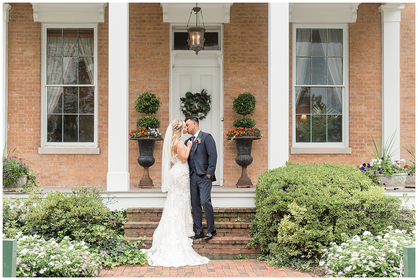 married couple kisses by front porch of historic home at Antrim 1844 venue in Maryland on sunny day