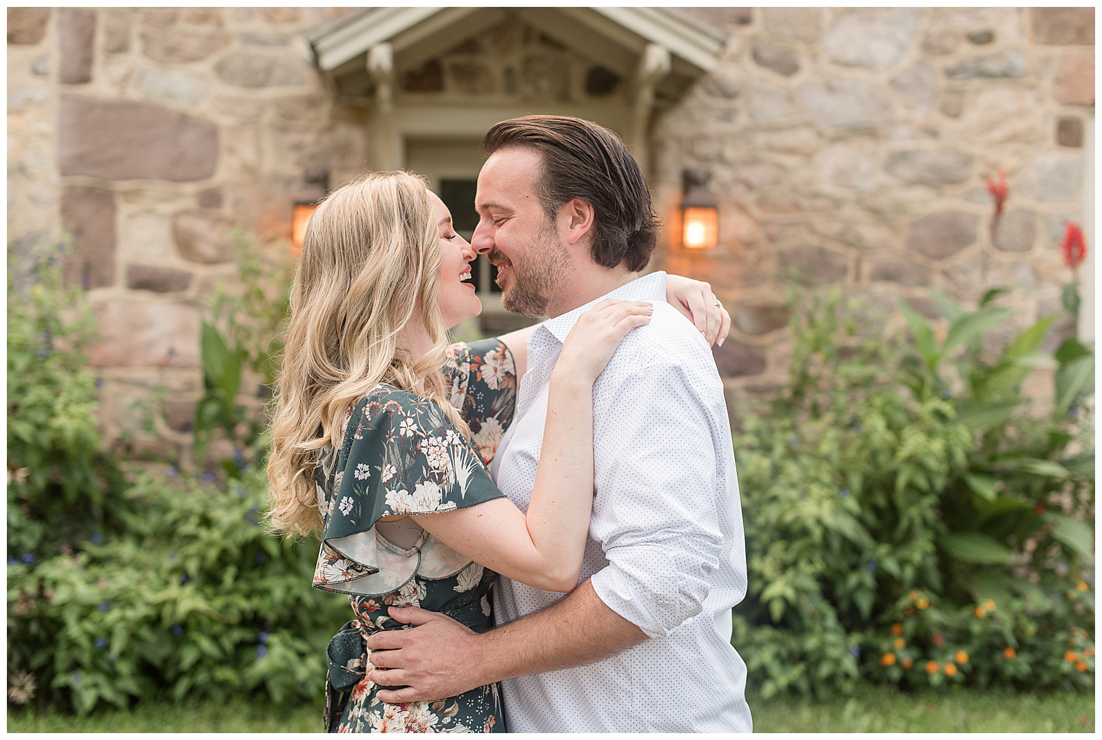 engaged couple hugging tightly with noses almost touching as they smile with stone building behind them at historic poole forge