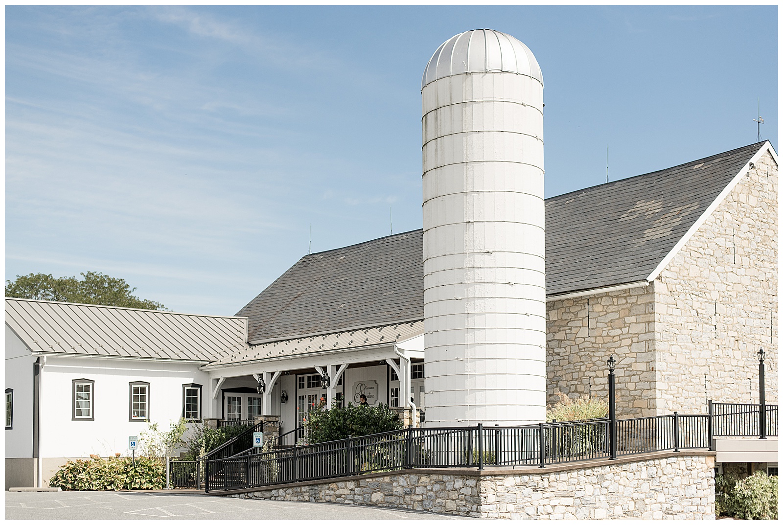 beautiful barn with white silo and patio with black wrought iron fence on sunny fall day at the barn at silverstone in lancaster pennsylvania