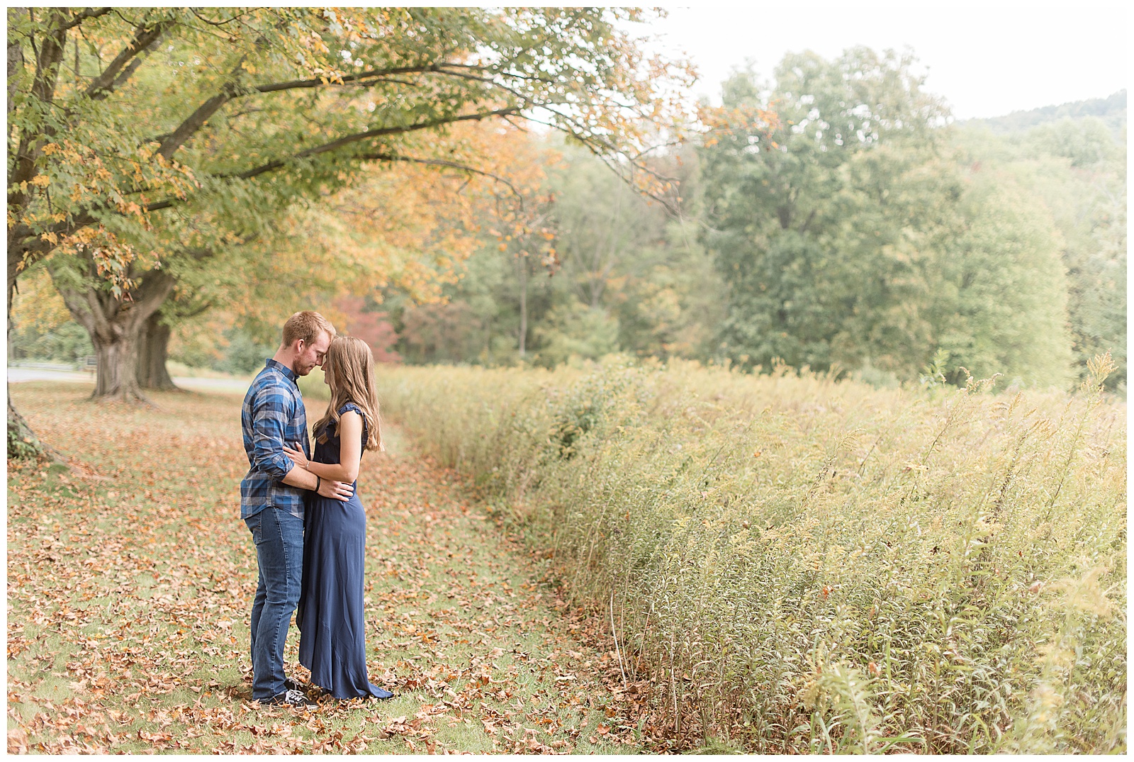 engaged couple standing close and facing each other along tall grasses under tree with colorful leaves at middle creek wildlife