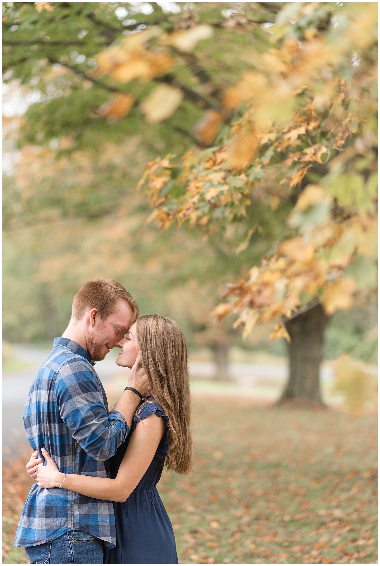couple hugging with foreheads touching with guy wearing blue flannel shirt and jeans and girl wearing dark blue dress in lancaster pennsylvania