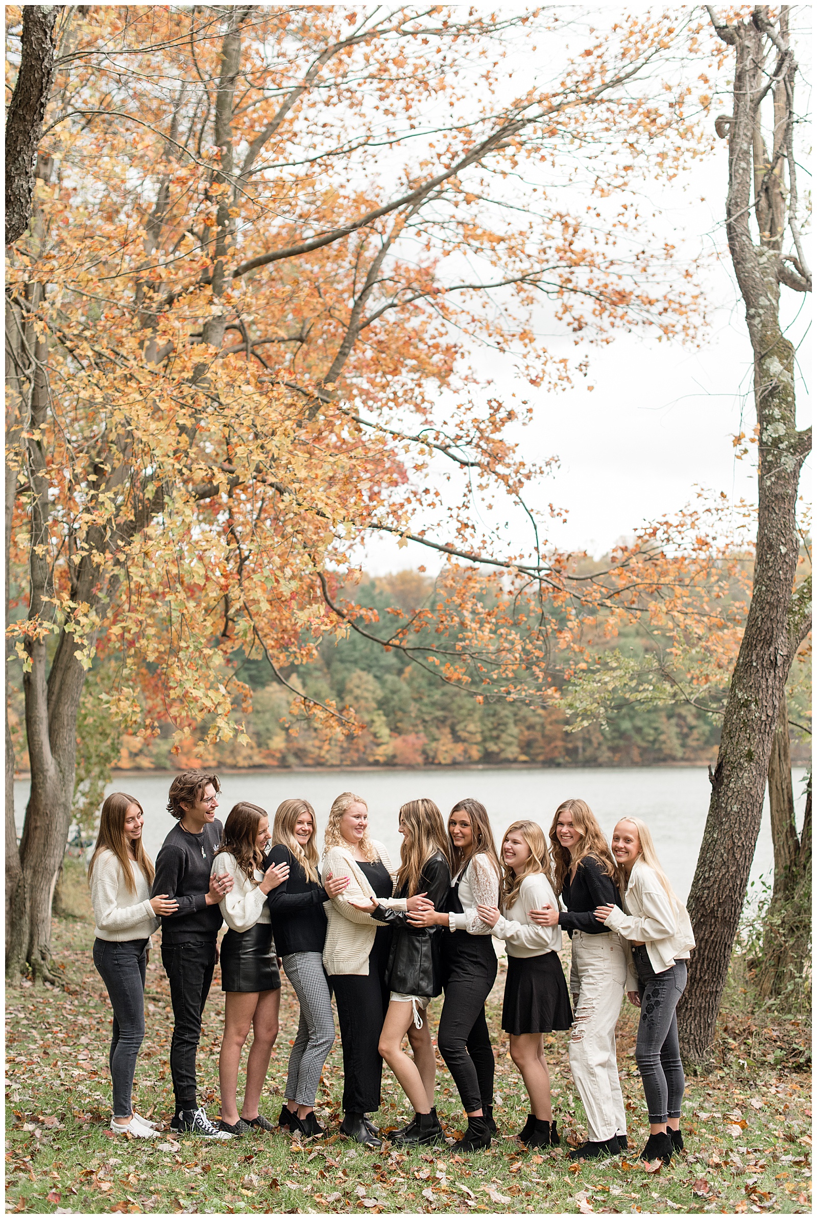 ten class of 2022 senior spokesmodels all huddled together under colorful fall tree at reservoir park in york pennsylvania