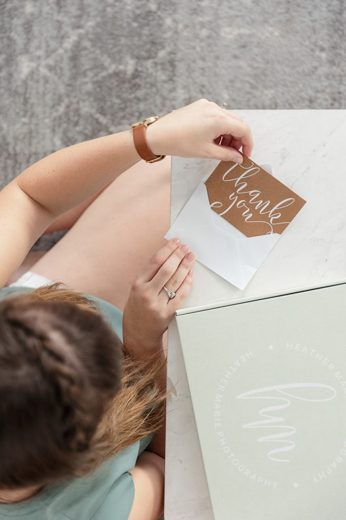 girl placing thank you note inside white envelope