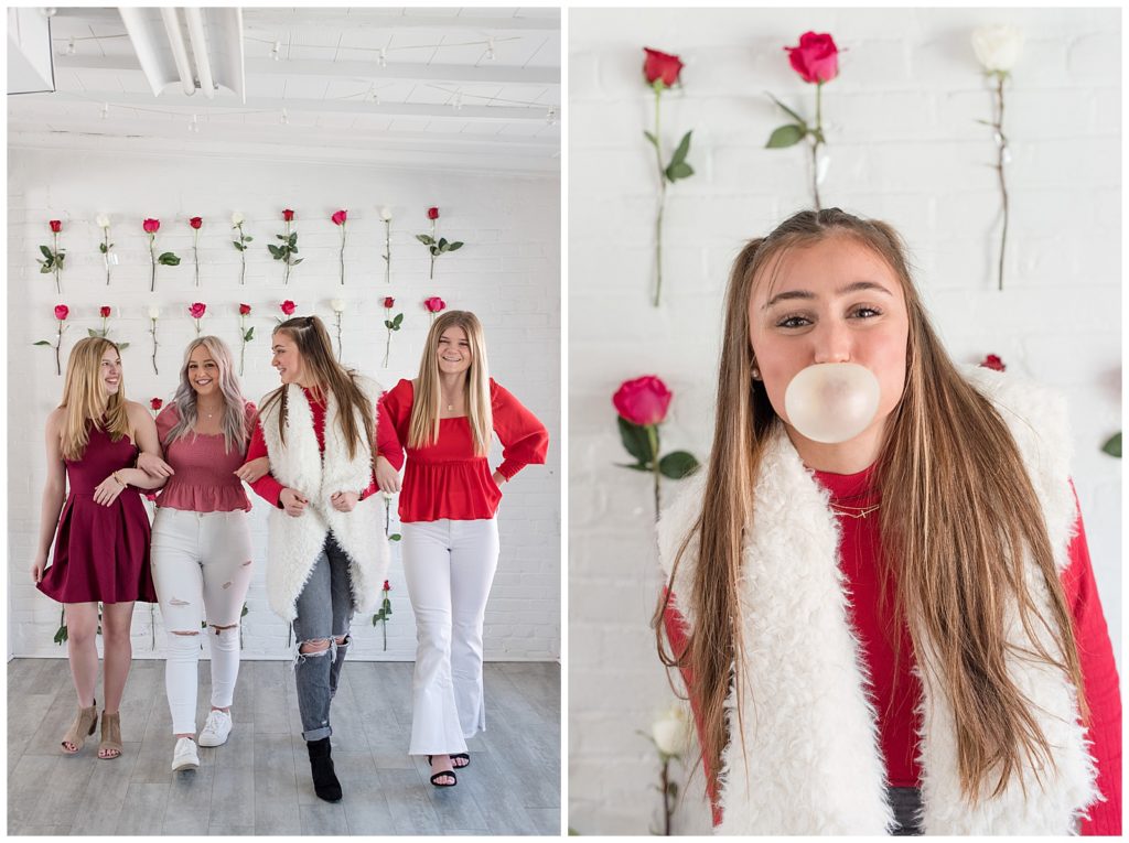 four seniors with arms linked walking toward camera by wall covered in roses