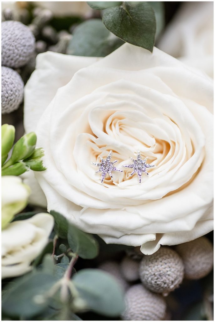 diamond earrings resting inside the petals of a white rose for lititz springs inn and spa wedding