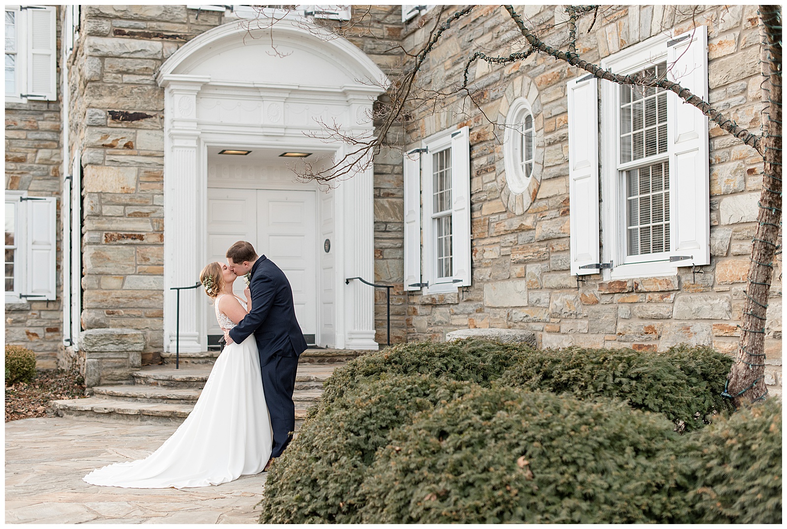 bride and groom kissing by steps of historic stone building on winter day in lancaster pennsylvania
