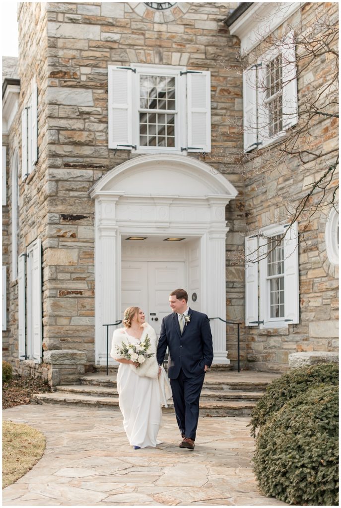 bride and groom smiling at each other holding hands outside historic stone building in downtown lititz pennsylvania
