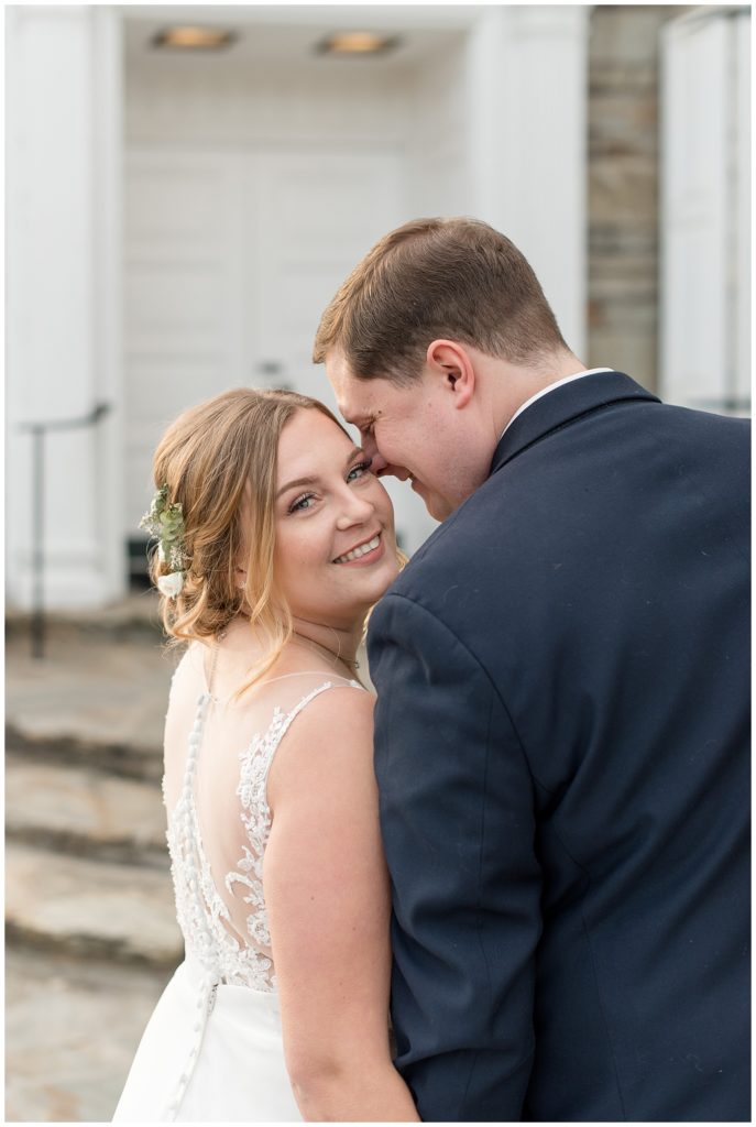 bride looking over right shoulder smiling at camera as groom leans against her in lititz pennsylvania