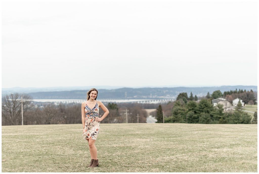 senior girl posing with left hand on hip in wide open grass field at samuel lewis state park