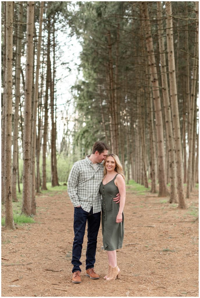 engaged couple hugging side by side among evergreen trees at overlook park in lancaster, pennsylvania