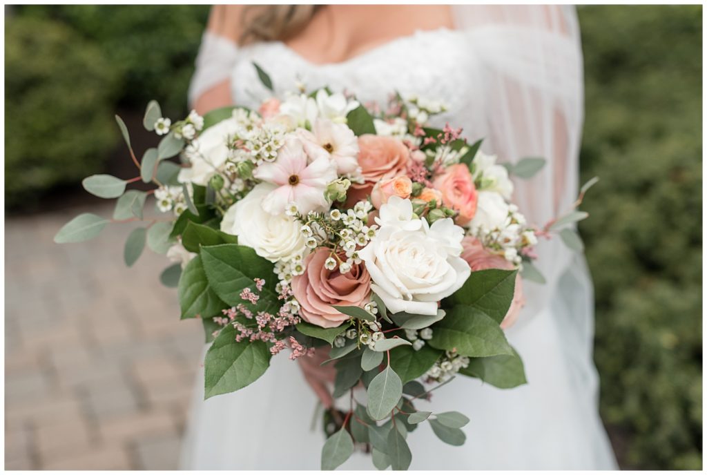 close up photo of bride's bouquet filled with blush and white roses and eucalyptus at the inn at leola village