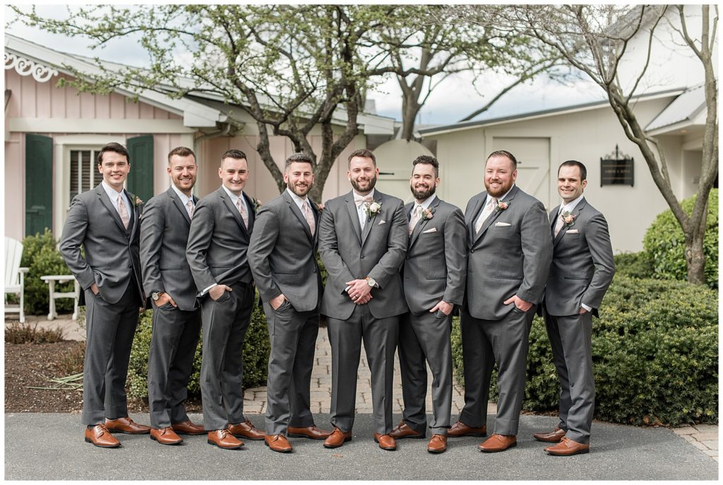 groom with his seven groomsmen all wearing dark gray suits at the inn at leola village