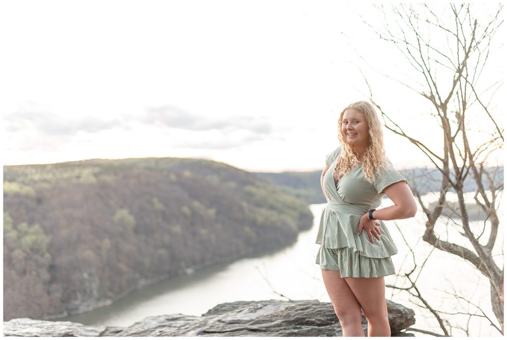 senior girl in short mint green dress atop large rocks at pinnacle point near susquehanna river on sunny evening