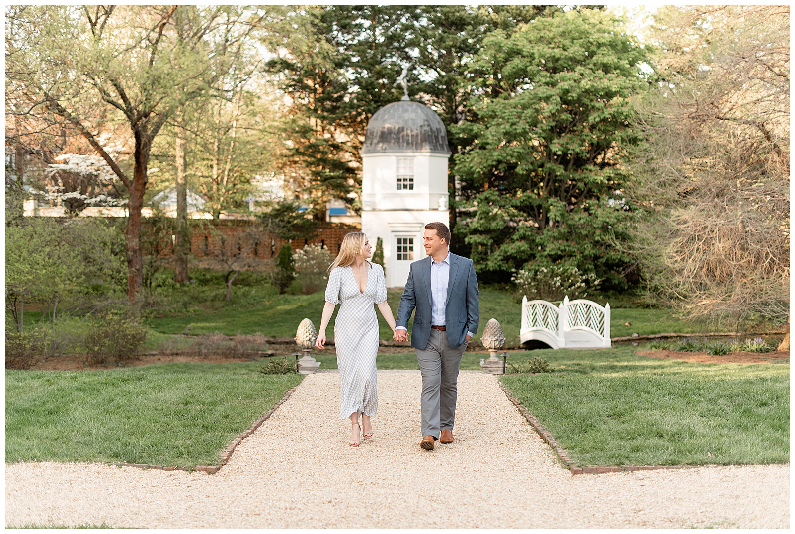 engaged couple holding hands and walking towards camera as they look at each other in annapolis maryland