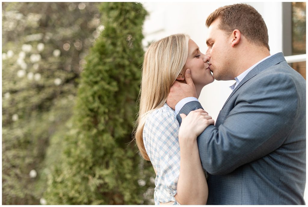 engaged couple kissing as guy holds girl's neck gently on sunny spring evening in annapolis maryland