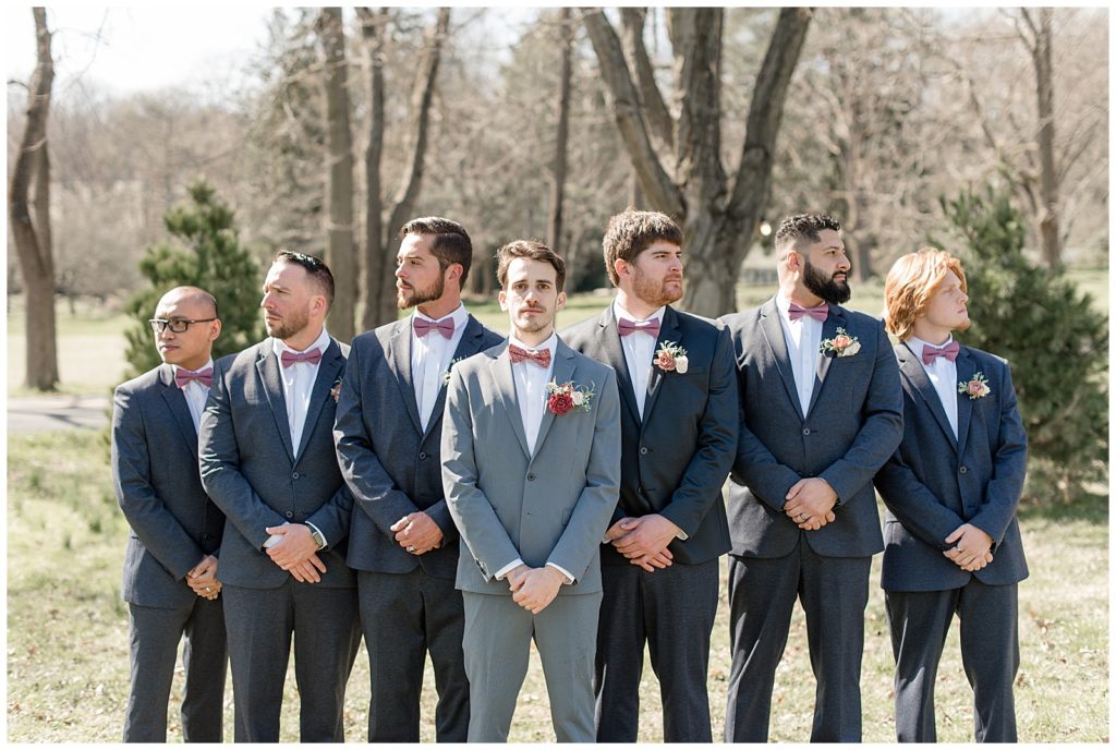 groom looking at camera as his six groomsmen look to the sides at stock's manor