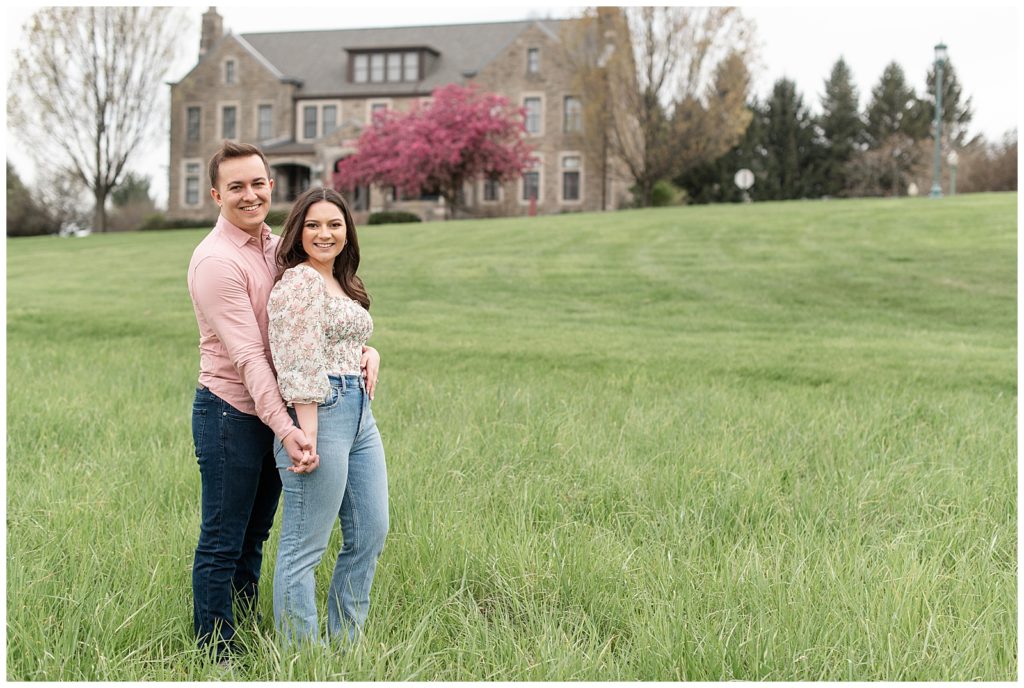 engaged couple wearing pinks and blues in lawn by historic building at masonic village in elizabethtown pennsylvania