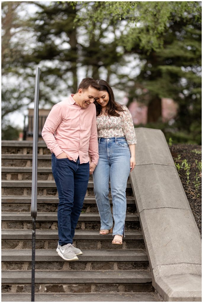 engaged couple holding hands as they walk down steps looking at their feet in lancaster county