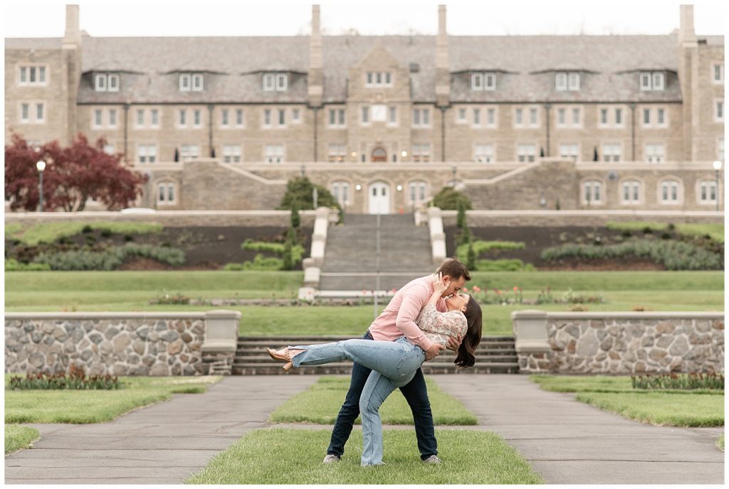 guy dipping girl back as they kiss on lawn in front of huge building at masonic village