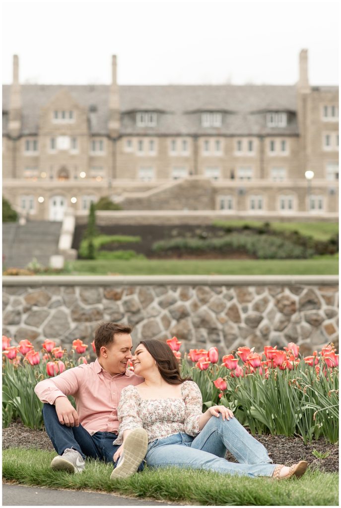 couple sitting on grass by tulips in front of large building at masonic village in lancaster pennsylvania