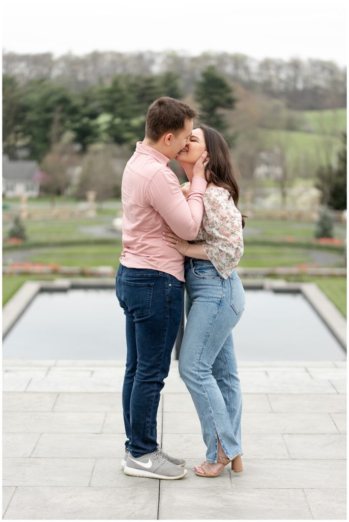 engaged couple kissing on stone walkway overlooking lawn at masonic village in elizabethtown pennsylvania