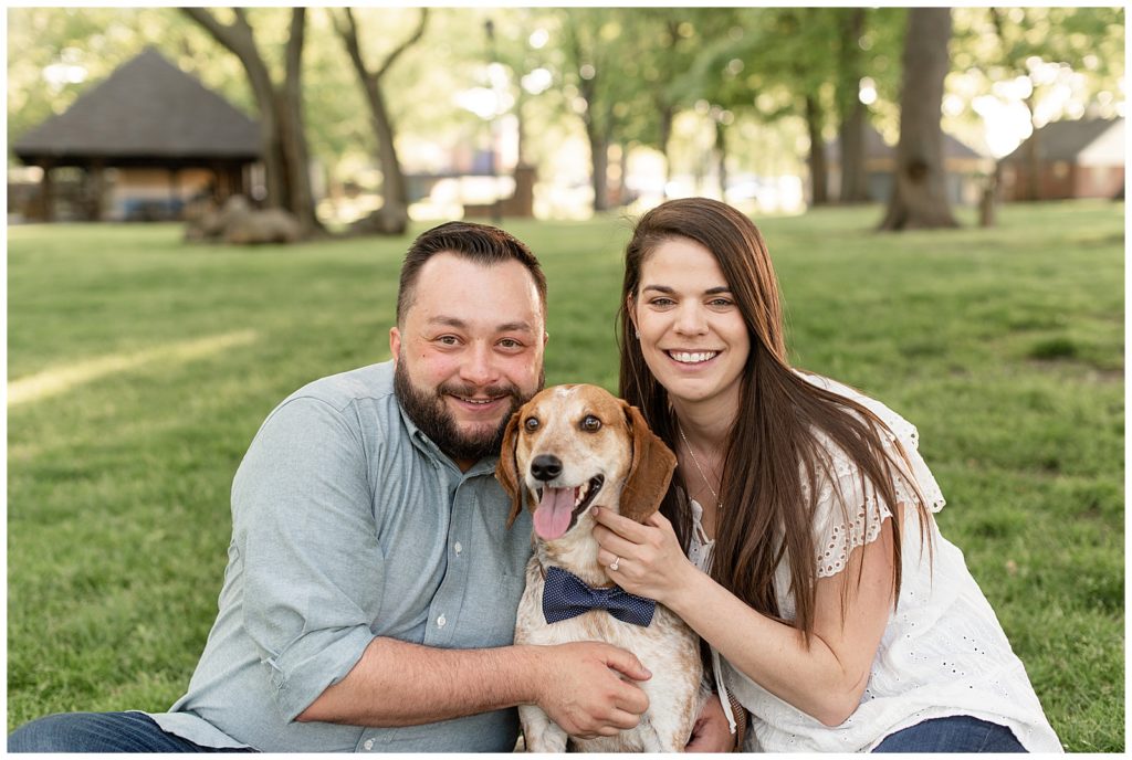 close up photo of engaged couple with their dog smiling at camera in lititz springs park