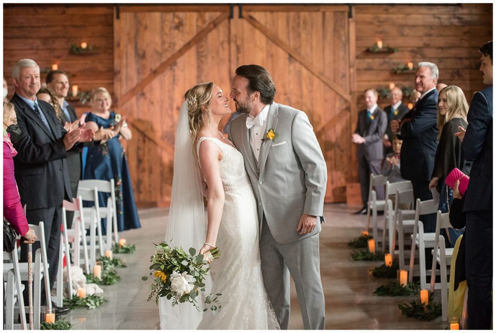 couple sharing a kiss as they leave their wedding ceremony inside rustic barn in lancaster pennsylvania