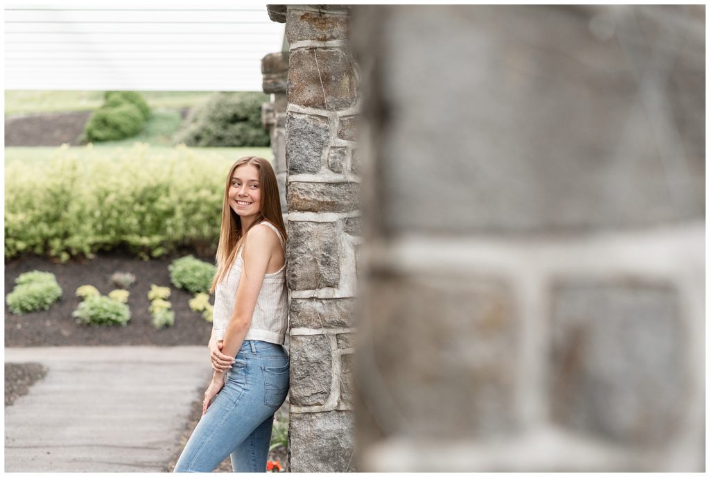senior girl leaning against beautiful gray stone wall and right shoulder towards camera in lancaster county pennyslvania