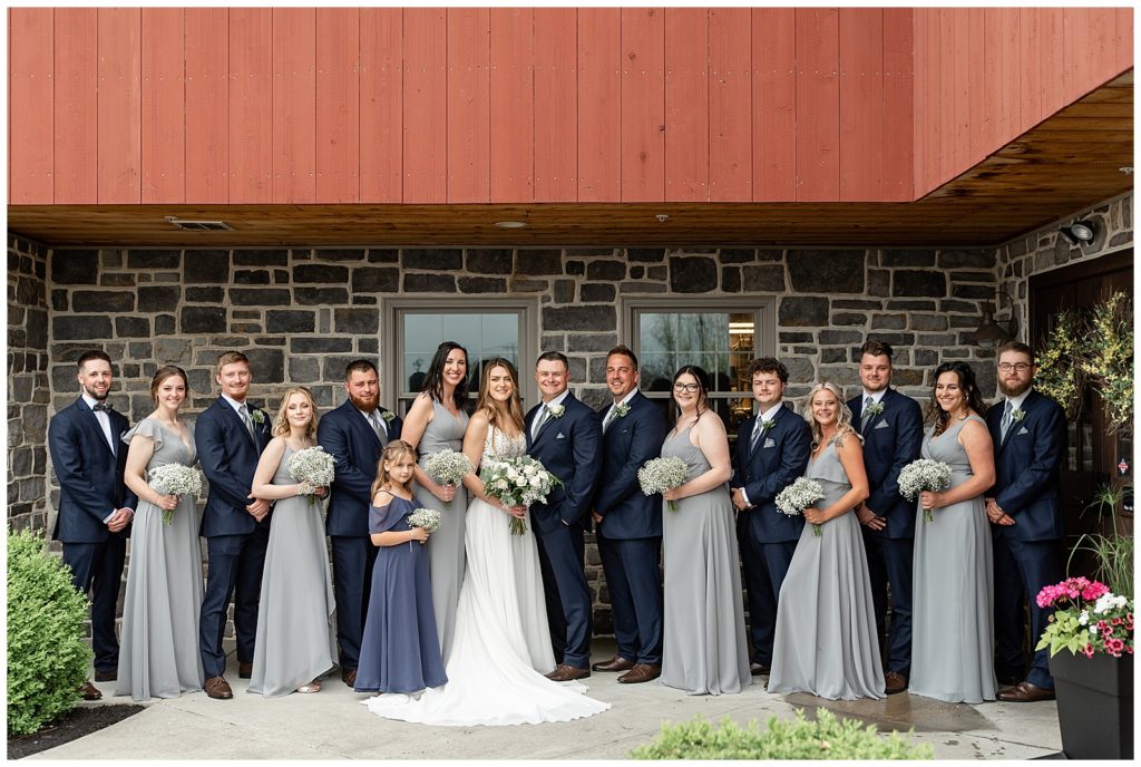 bride and groom with bridal party outside under barn roof at brick gables in lancaster county pennsylvania