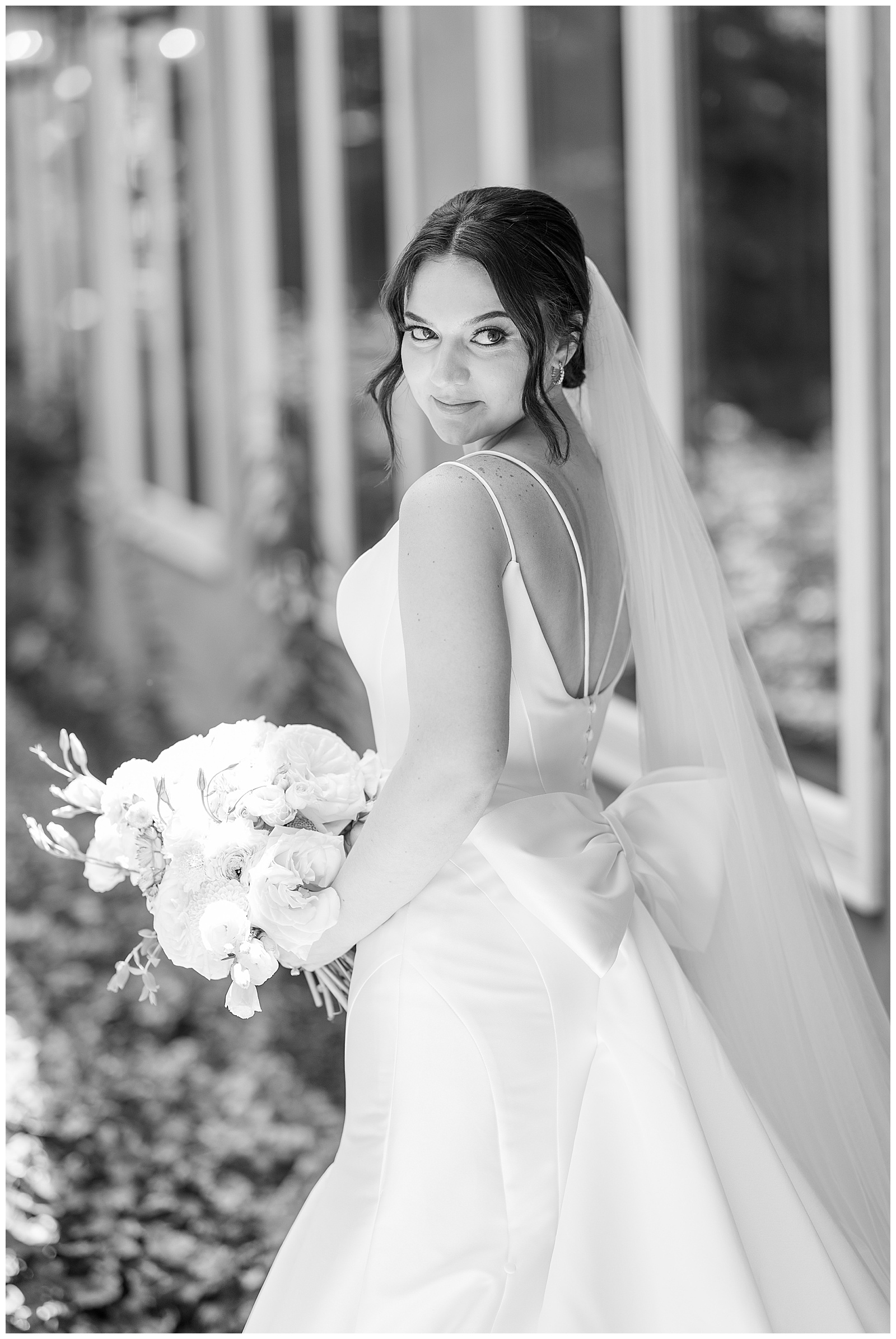 black and white photo of bride looking back over left shoulder in spaghetti strap white gown at cameron estate inn