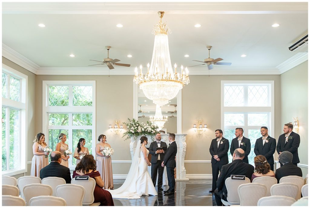 couple sharing their vows inside bright room with chandelier at cameron estate inn in lancaster county