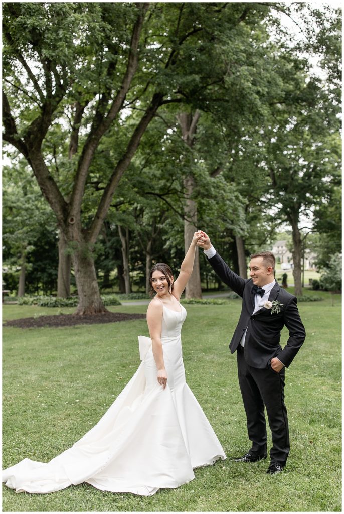 groom twirling his bride as she smiles and looks over right shoulder outdoors at cameron estate inn