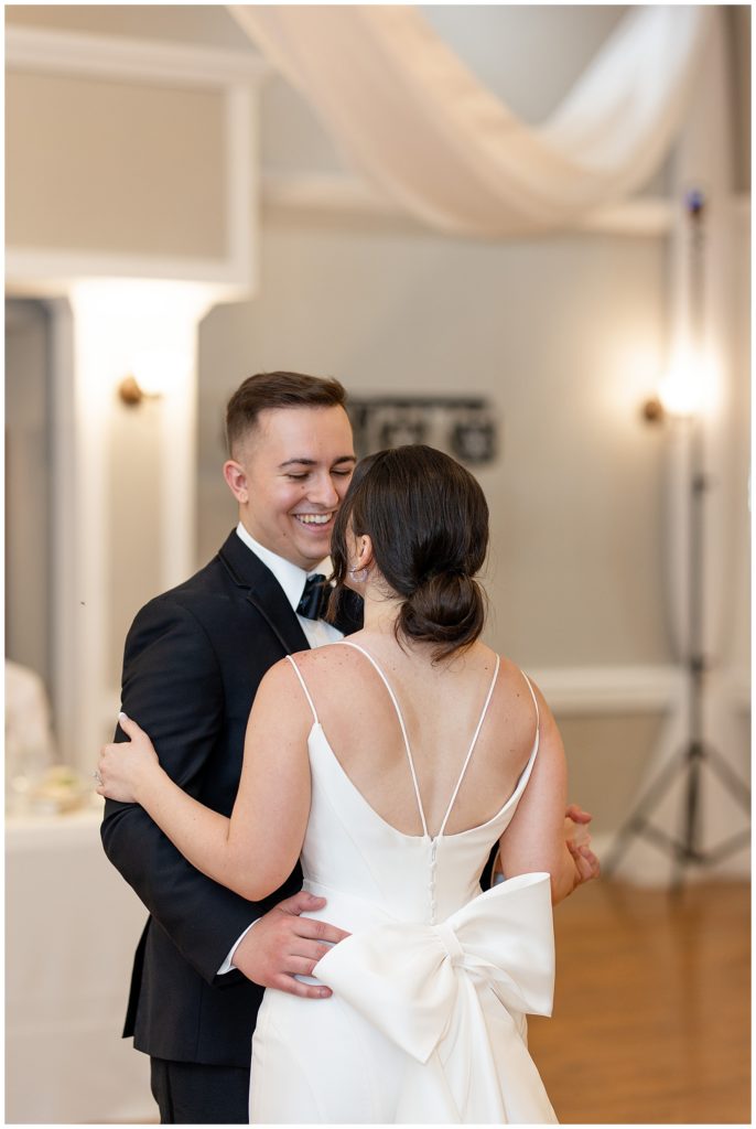 groom smiling at his bride as she has her back toward camera during their first dance at cameron estate inn