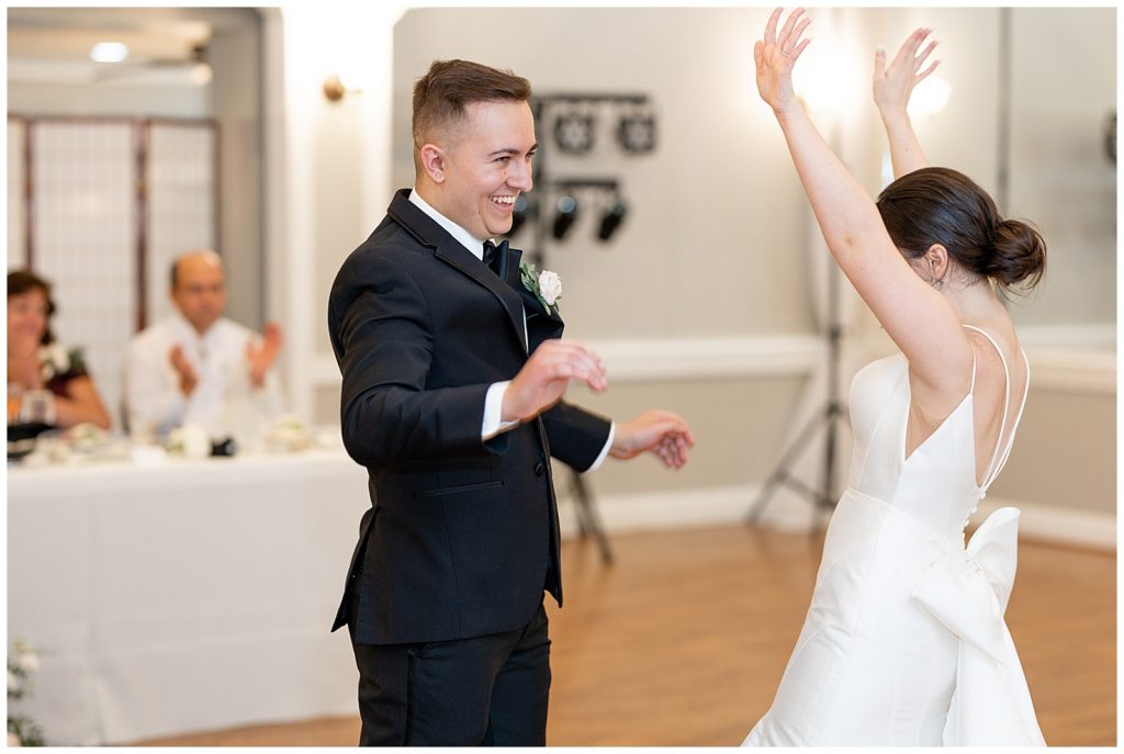 groom smiling at bride as her arms are raised overhead at the end of their first dance at cameron estate inn in mount joy pennsylvania