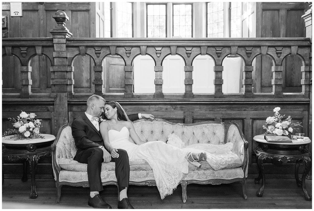 black and white photo of bride and groom sitting on old sofa inside historic building at parque ridley creek wedding in pennsylvania