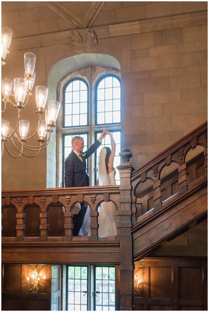 groom twirling his bride inside historic building with chandelier on staircase at parque ridley creek
