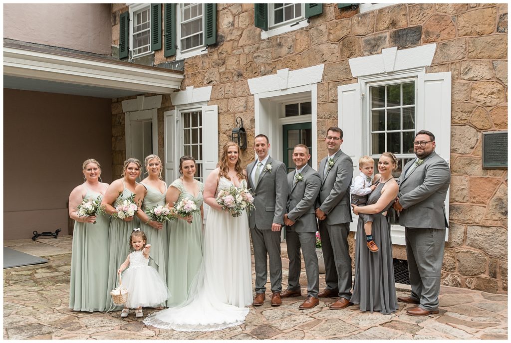 bride and groom with bridal party and flower girl and ring bearer outside stone home at elizabeth furnace