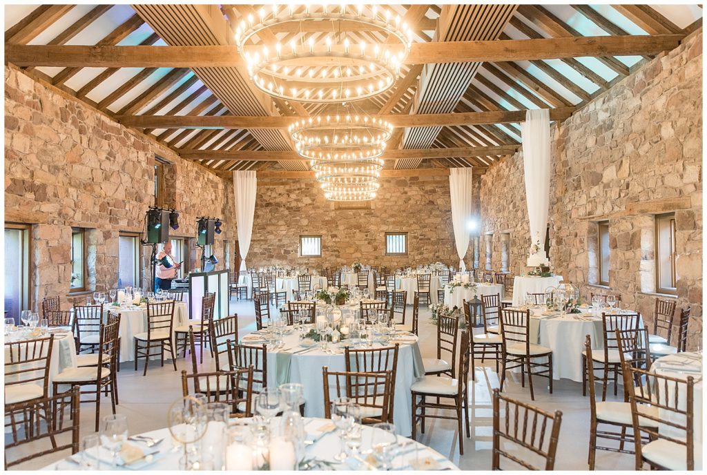 beautiful reception area inside stone barn with huge chandeliers and tables and chairs at elizabeth furnace