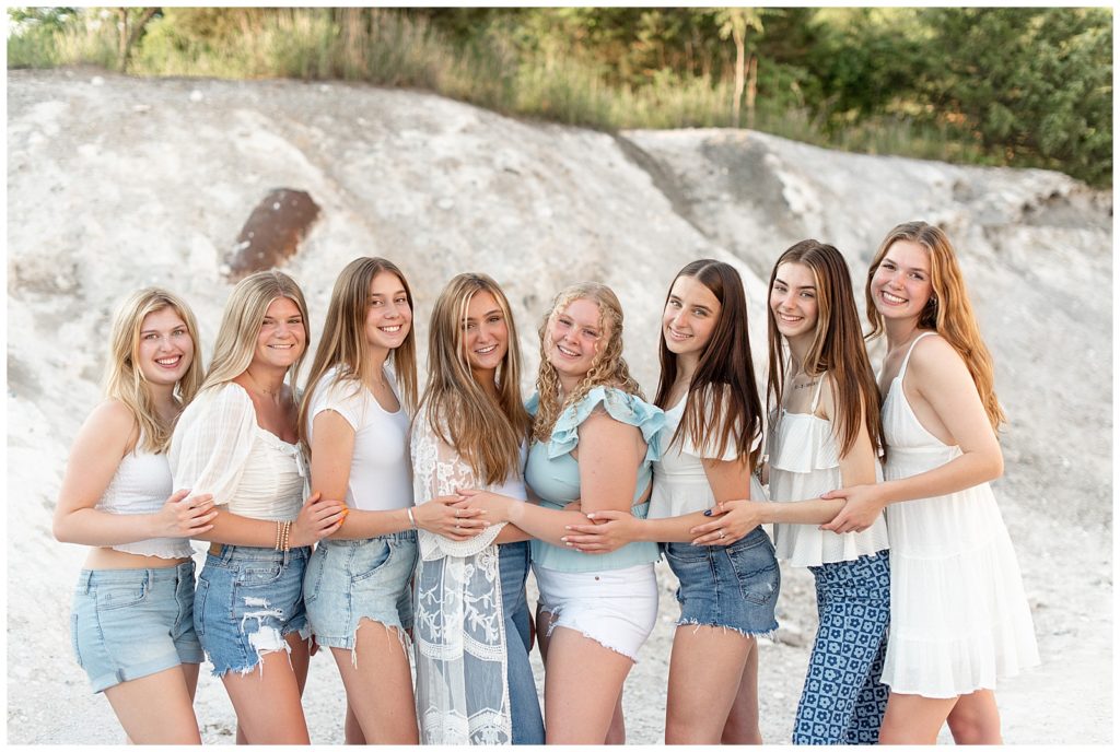eight senior girls facing towards one another with their hands resting on the elbow of the girl beside her in lancaster county