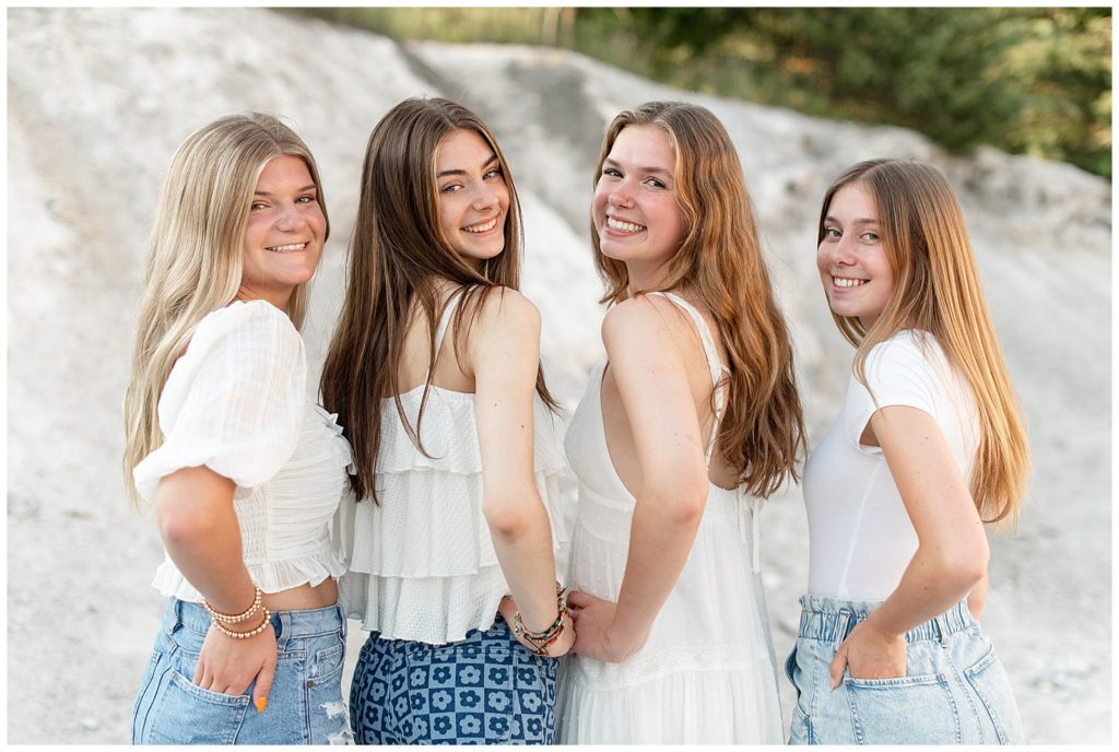 four senior girls with their backs toward camera looking back over their shoulder at the white cliffs of conoy