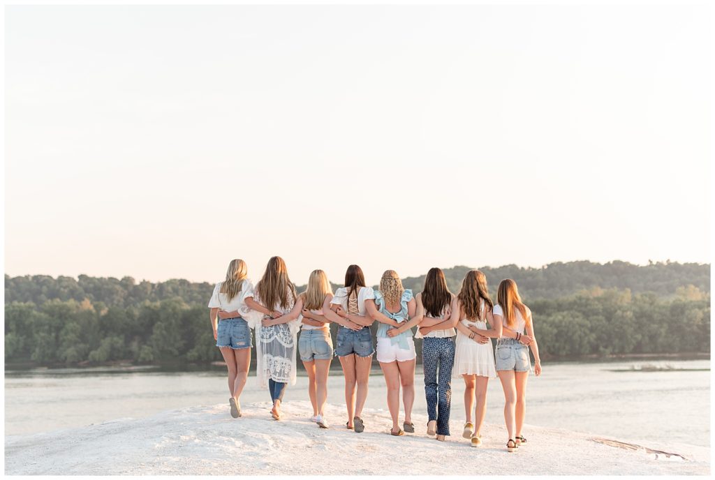 eight senior girl spokesmodels with their arms around each other as they're walking away from the camera on sunny evening at the white cliffs of conoy