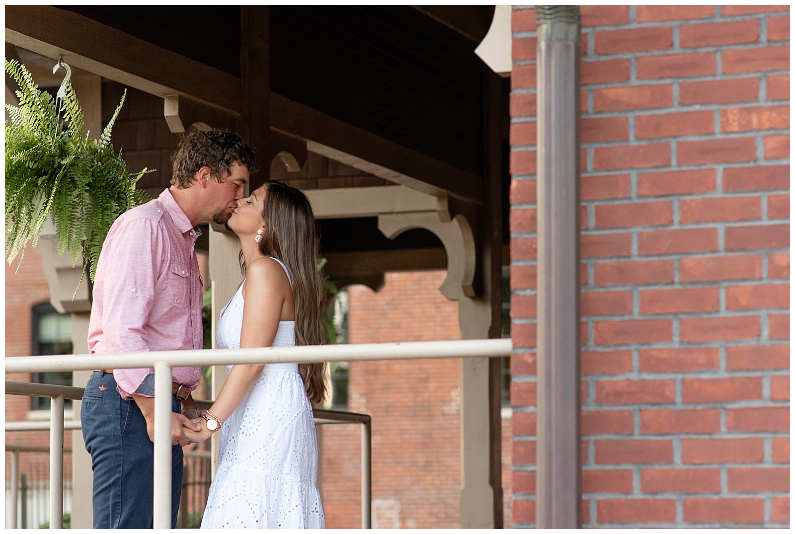 engaged couple kissing on porch of brick building in downtown lititz pennsylvania