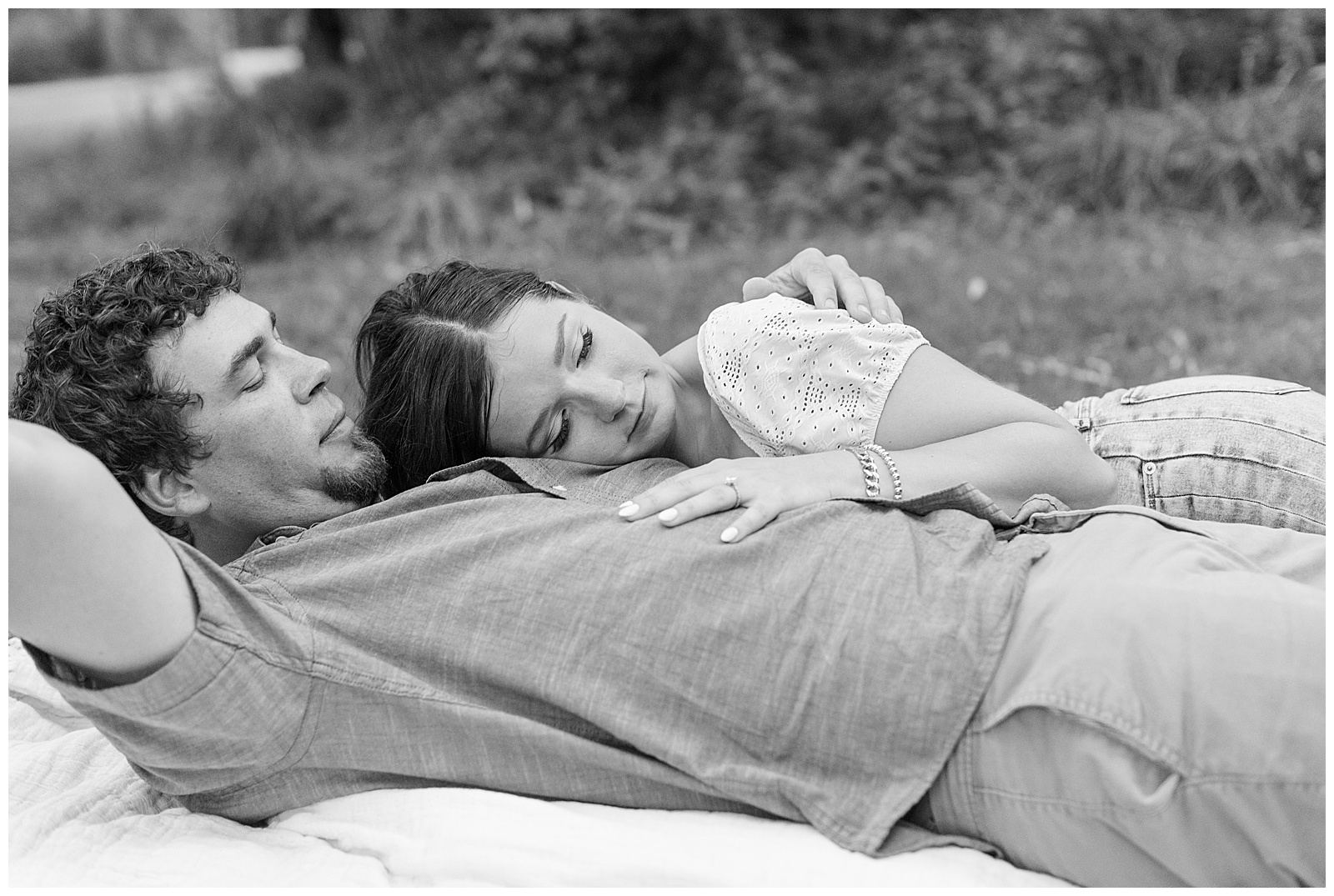 black and white photo of guy laying back on picnic blanket as girl lays on his chest at overlook park