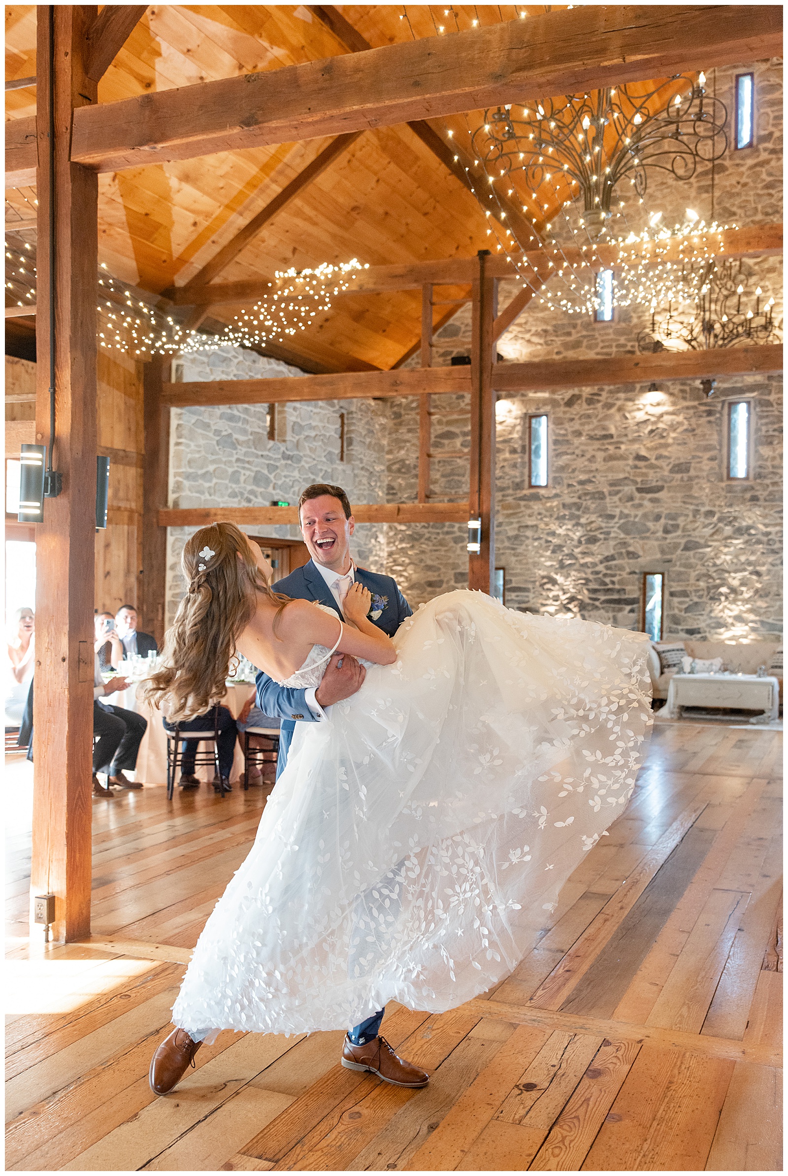 groom lifting his bride and swinging her on the dance floor inside stunning barn reception at the barn at silverstone