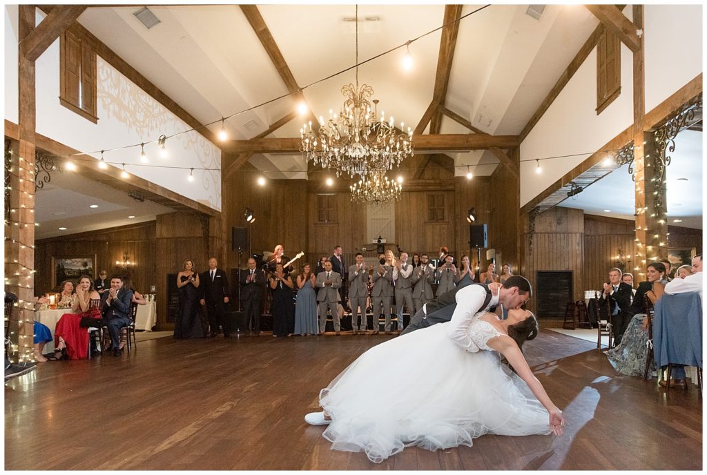 groom dipping his bride way back during their first dance at indoor reception at normandy farms