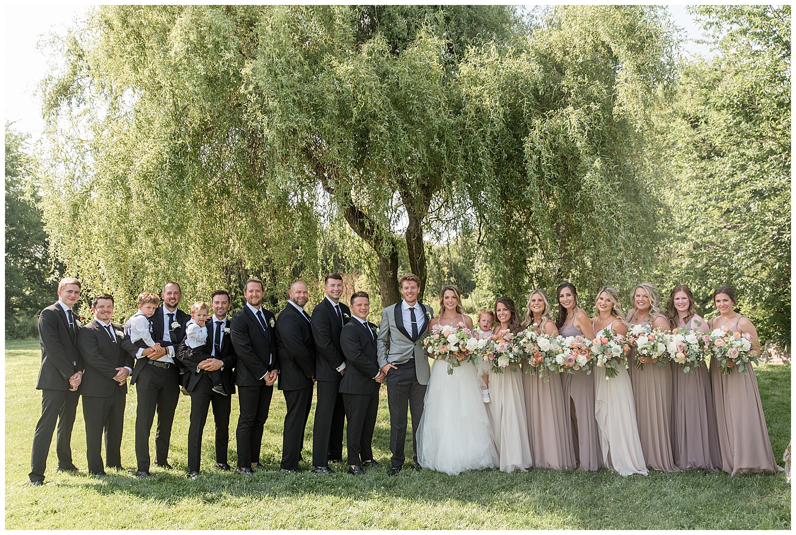 bride and groom with their bridal party under willow tree at the barn at silverstone in lancaster county