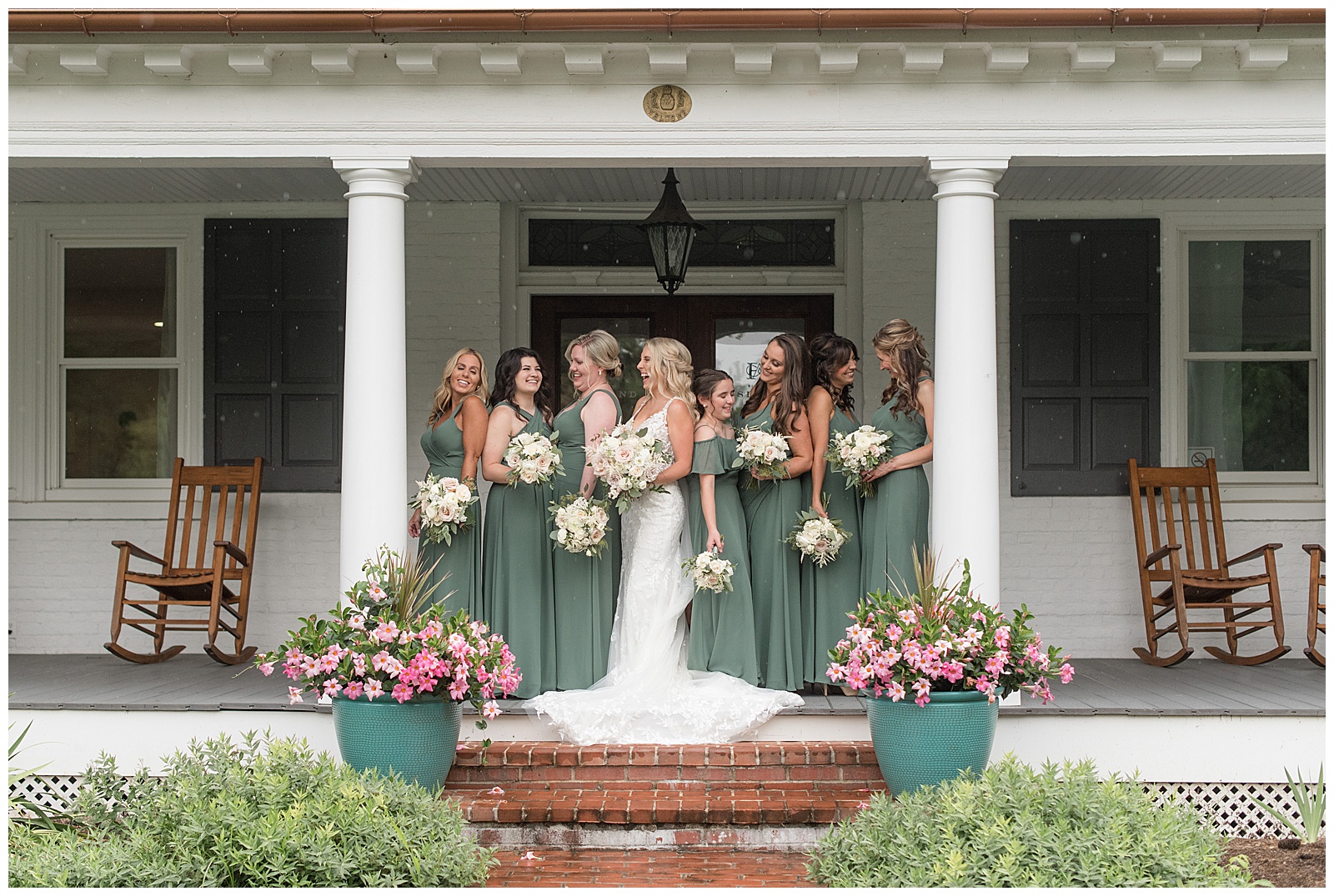 bride surrounded by her seven bridesmaids in muted green gowns on farmhouse front porch in wrightsville pennsylvania