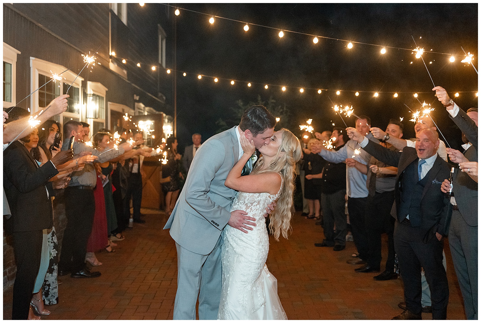 couple sharing a kiss in between aisle of guests with sparklers as they leave their reception at historic ashland