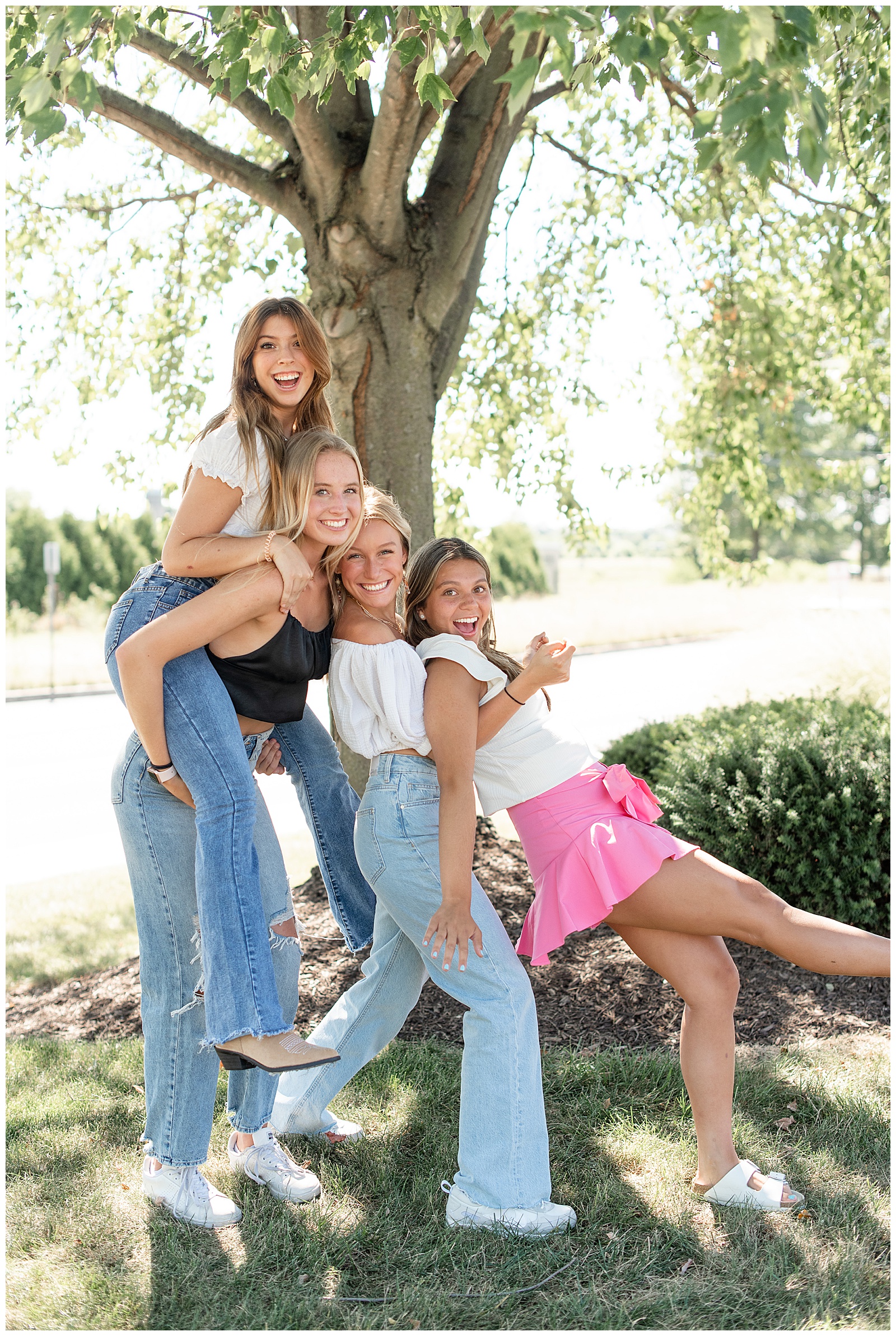 one senior girl piggybacking on another girl and two other girls leaning into them in lancaster county